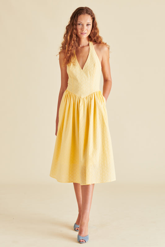 A model wearing a yellow sleeveless midi dress with a V-neckline and a pleated skirt.