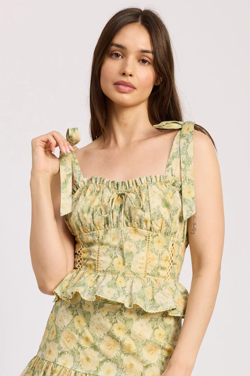 Woman wearing a floral top with ruffled details on a light background