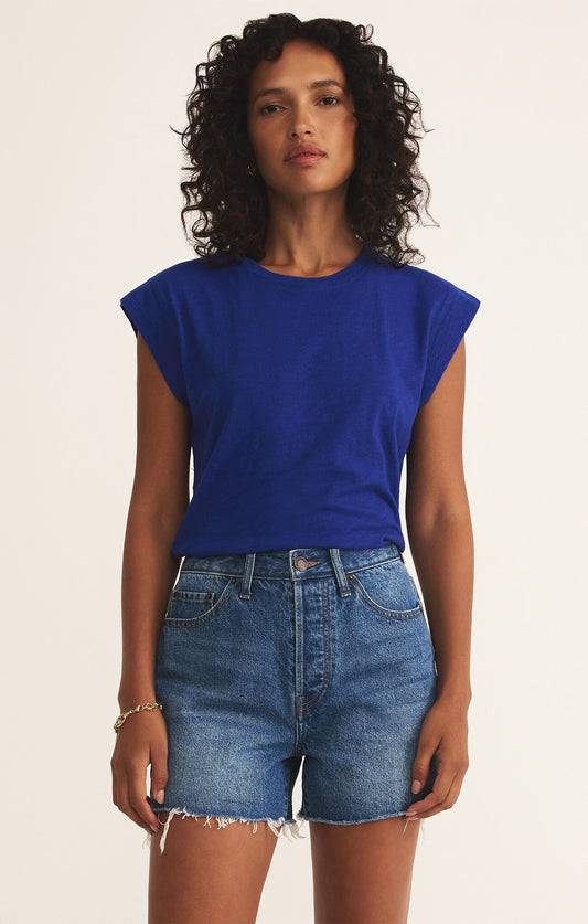 Woman wearing a blue top and denim shorts on a beige background