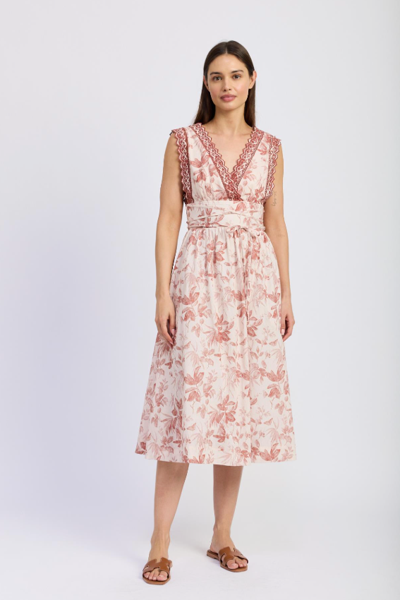 A woman wearing a beautiful pink and white Sedona Midi Dress with floral embroidery.