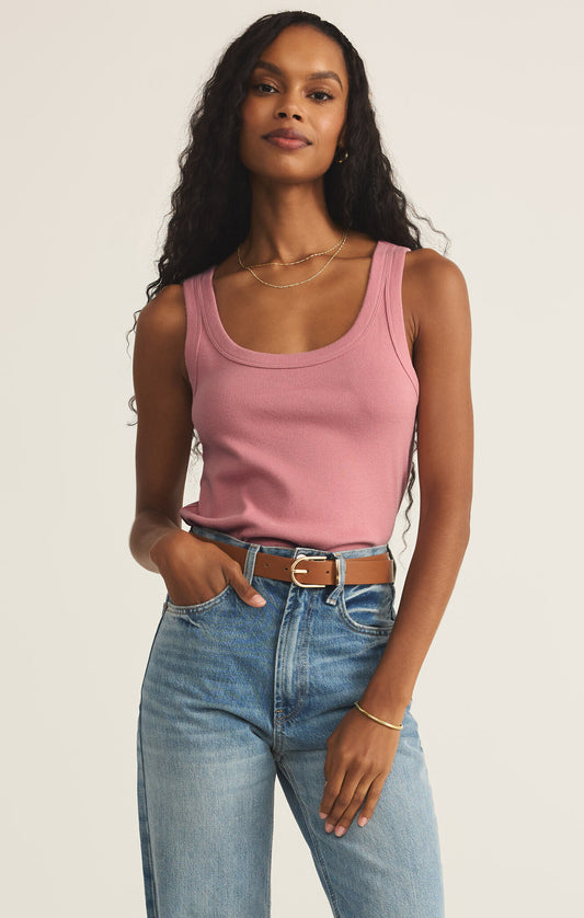 A female model wearing a pink ribbed tank top and blue jeans.