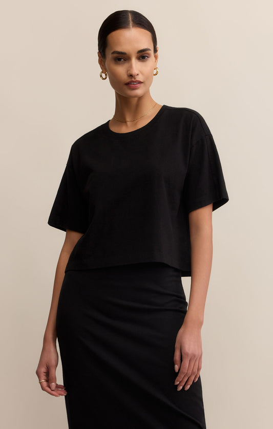 Woman wearing a black outfit against a beige background