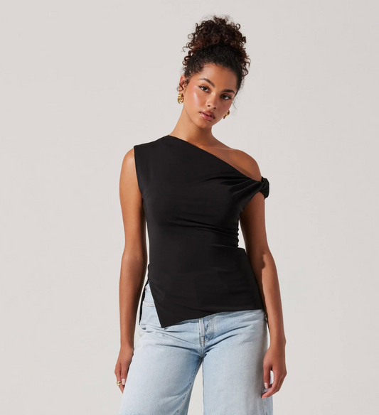 Woman wearing a black one-shoulder top and light blue jeans against a plain background