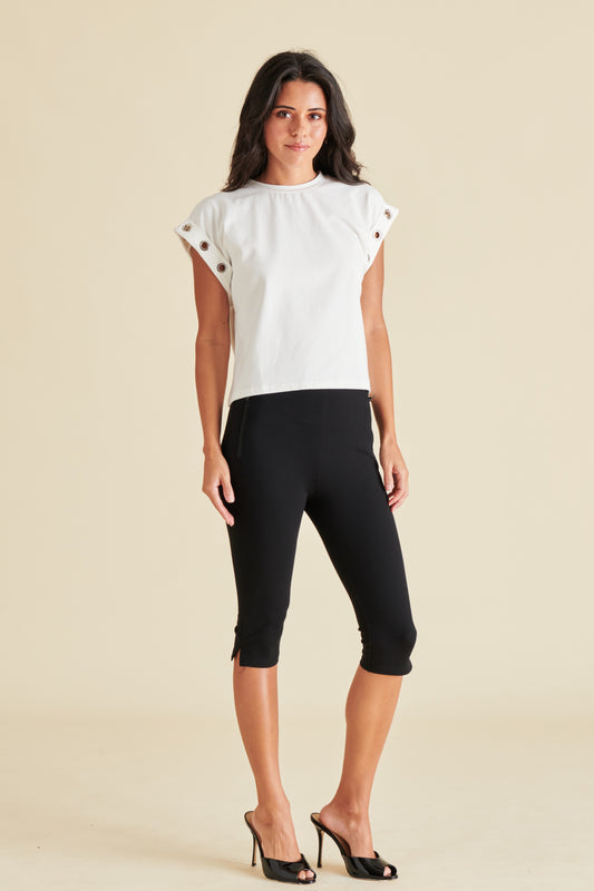 A woman modeling a white short sleeve top with black capri pants.