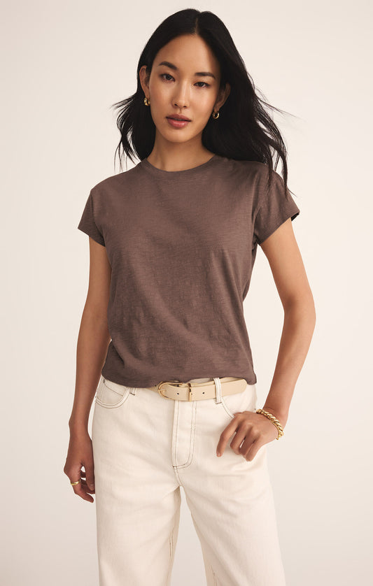 Woman wearing a brown t-shirt and white pants on a plain background