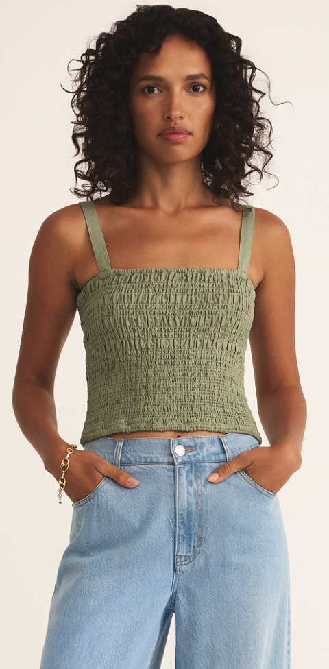 A female model wearing a green linen top with short sleeves and blue jeans.