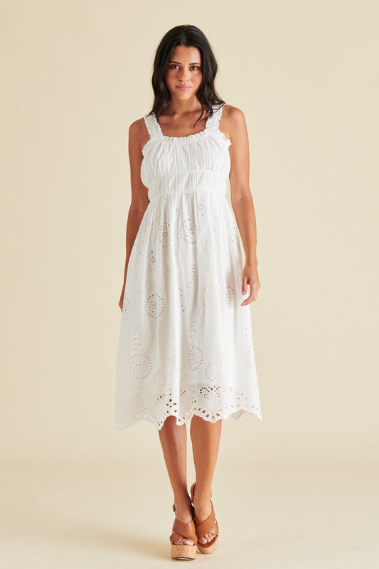 A woman wearing a white dress with a subtle floral pattern.