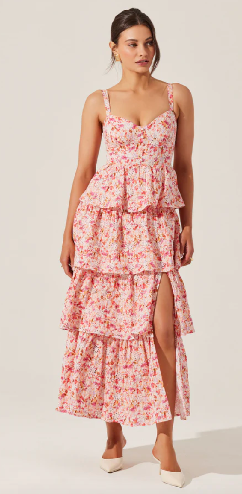 A woman smiling while wearing a pink floral Midsummer Dress from a lifestyle boutique.