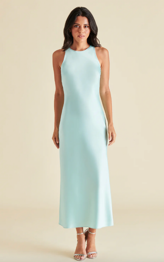 A woman standing in a plain, baby-blue dress.