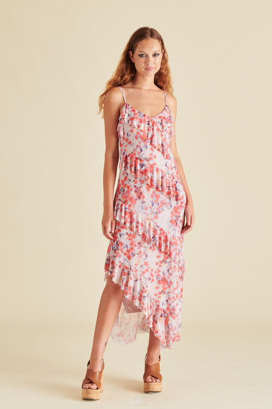 A woman posing in a pink floral dress with a ruffled texture.