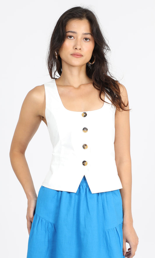 A woman wearing a white sleeveless top with buttons at the neckline, paired with a blue skirt.