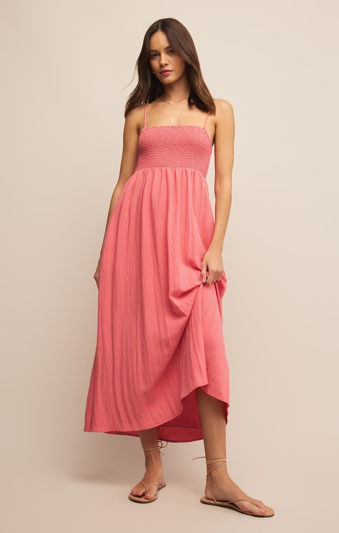 A woman posing in a long, rose-pink dress.