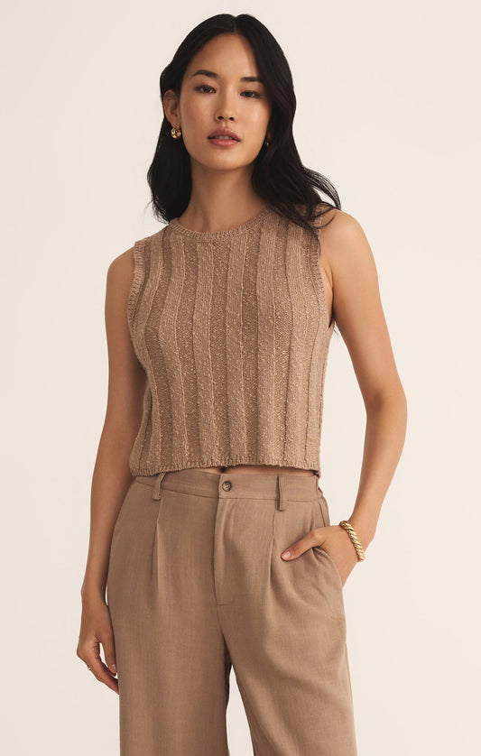 A woman wearing a beige, short sleeve, solid pattern top.